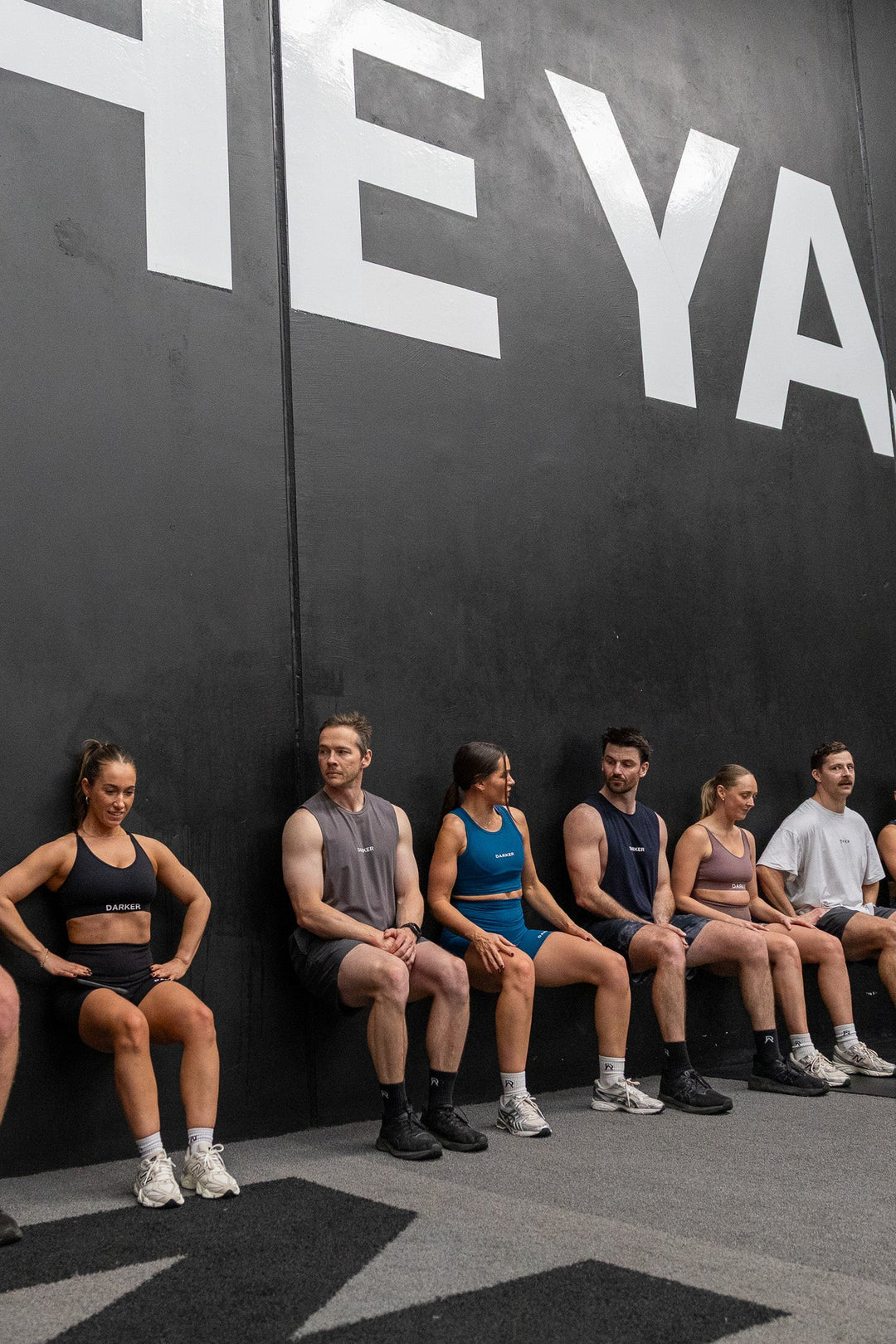 Group of men and women sitting against a wall at The Yard gym in Darker Apparel Agile activewear