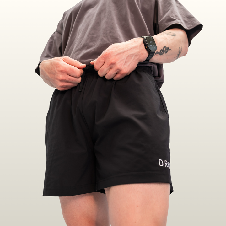 Man adjusting the waistband of the black Endure 5 inch Shorts
