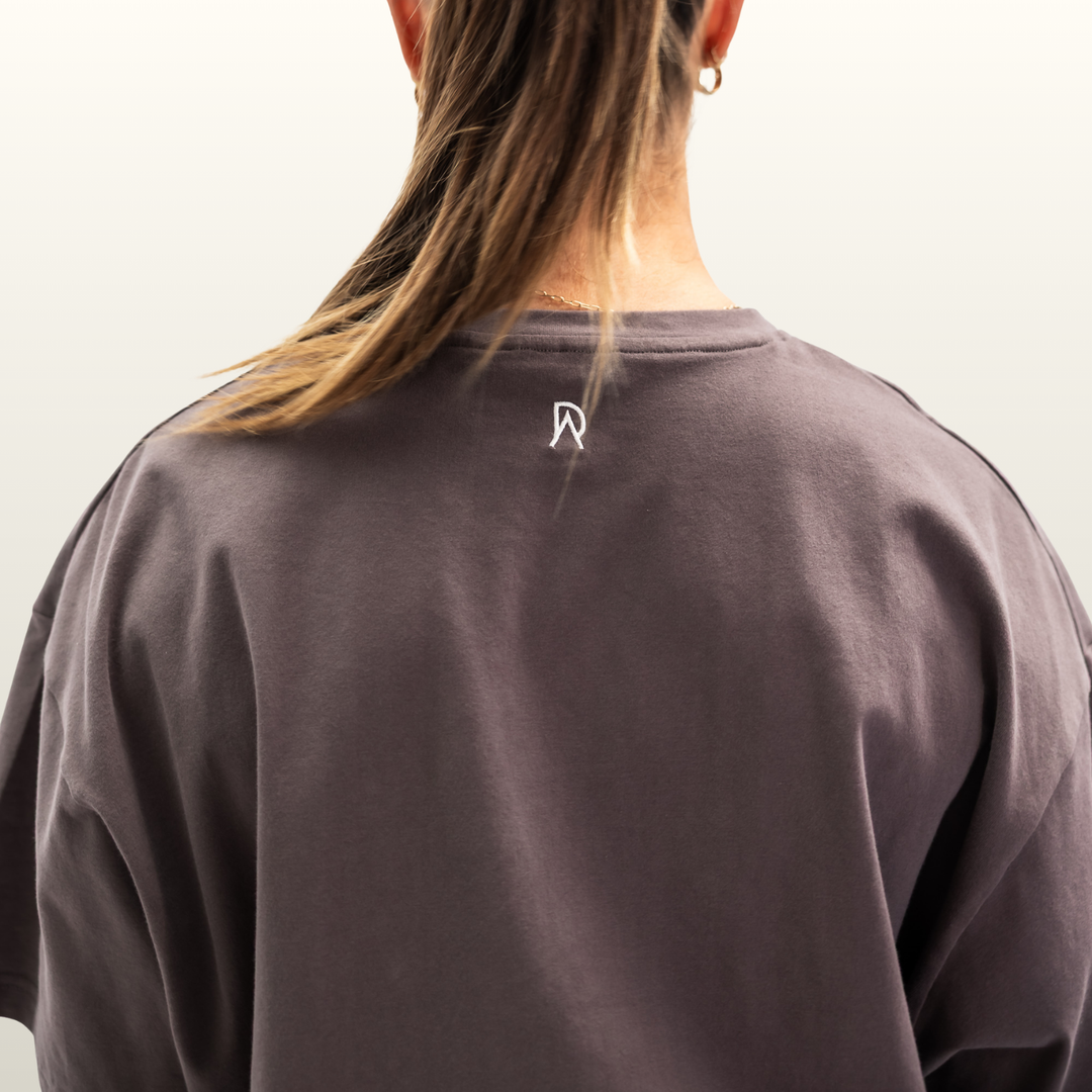 Close-up of the DA monogram on the back neck of the storm grey Endure Oversized Tee