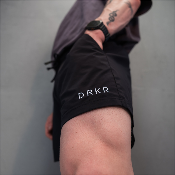 Close-up of the DRKR leg logo on the black Endure 5 inch Shorts