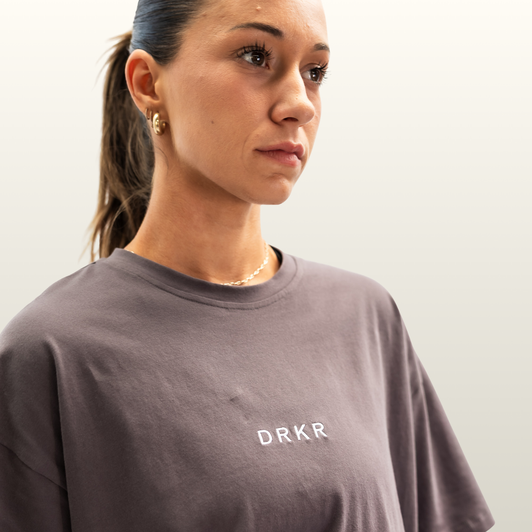 Close-up of the DRKR chest logo on the storm grey Endure Oversized Tee