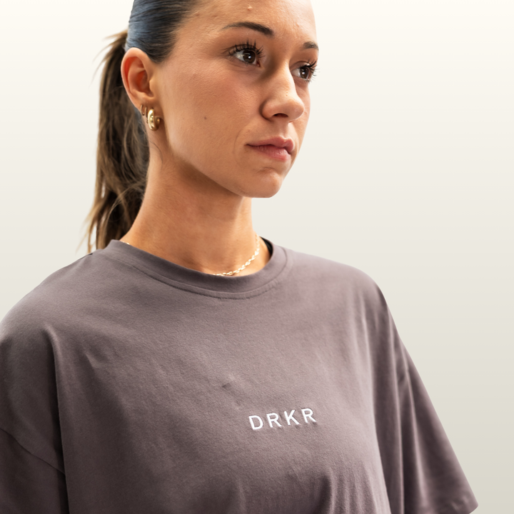 Close-up of the DRKR chest logo on the storm grey Endure Oversized Tee