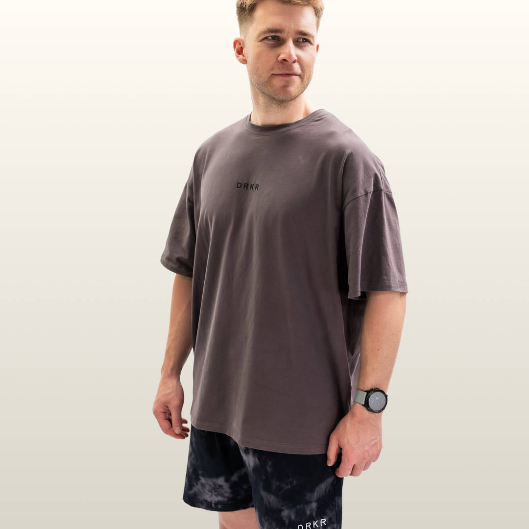 Man wearing the Endure Oversized Tee in storm grey with Endure Shorts in midnight camo, three-quarter view