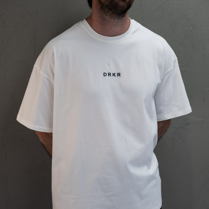 Close-up of the white Endure Oversized Tee showing the DRKR chest logo and dropped shoulders