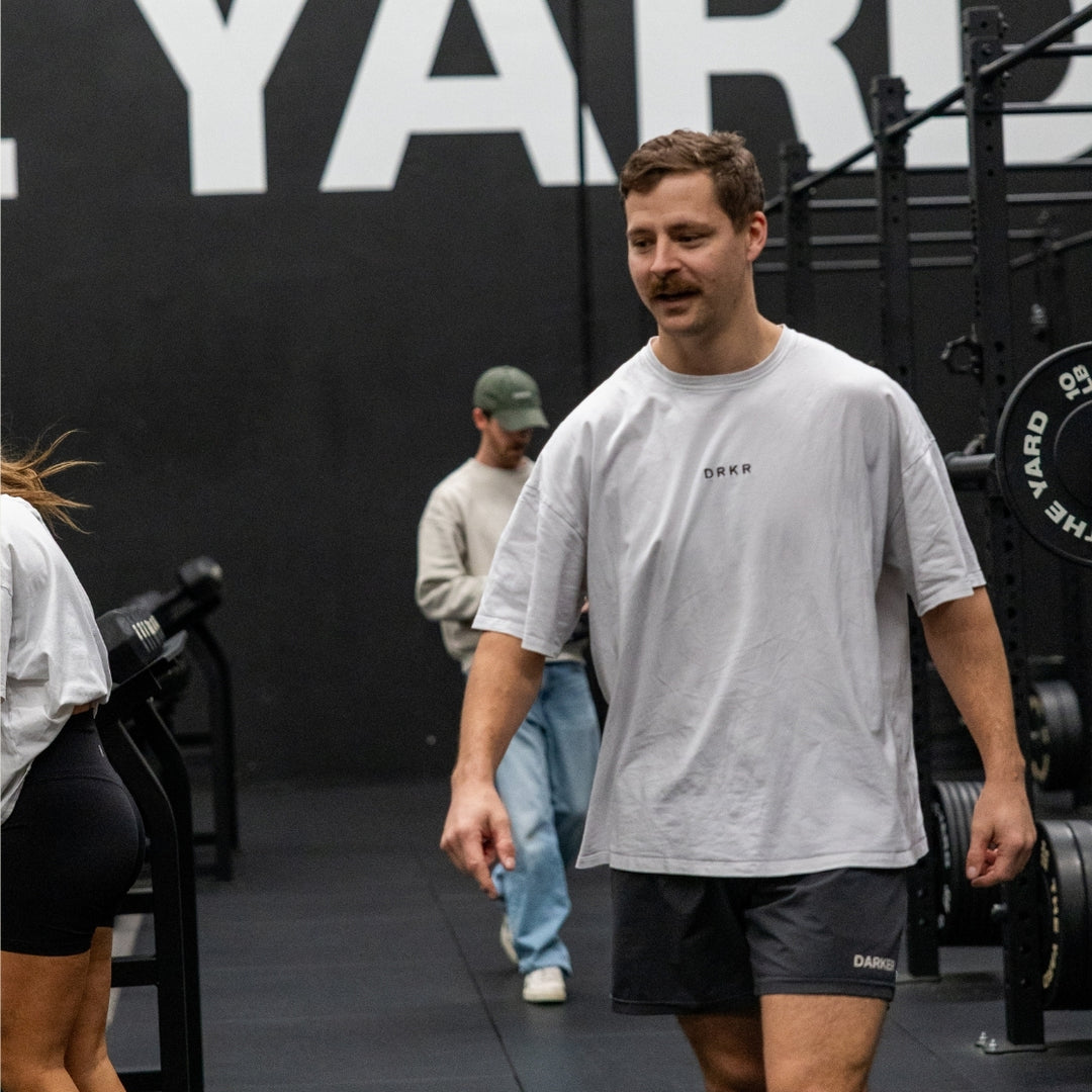 Man walking through the gym in a white Endure Oversized Tee and Endure Shorts