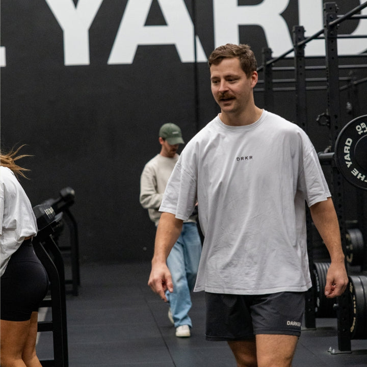 Man walking through the gym in a white Endure Oversized Tee and Endure Shorts
