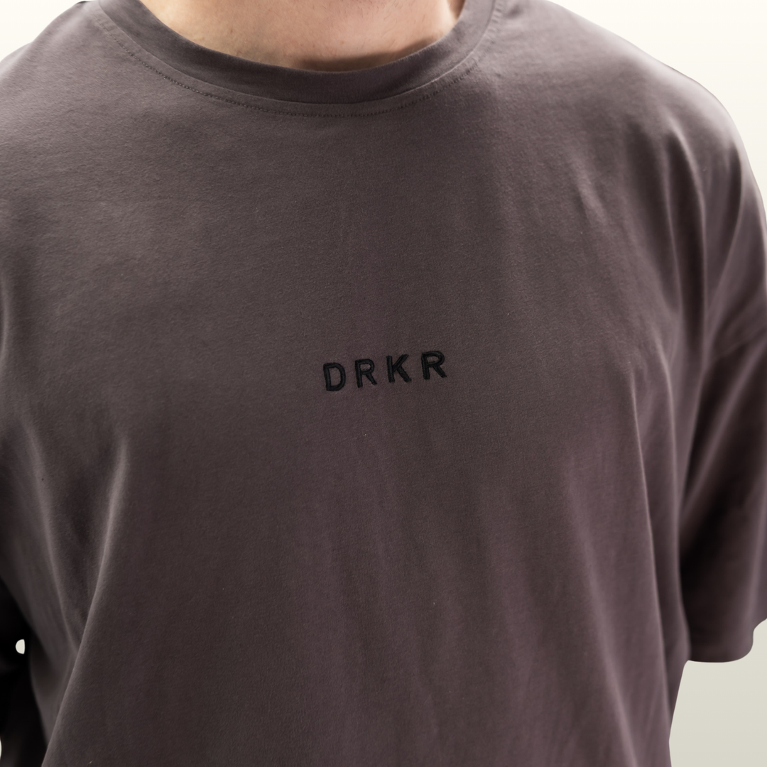 Close-up of the DRKR chest logo on the storm grey Endure Oversized Tee