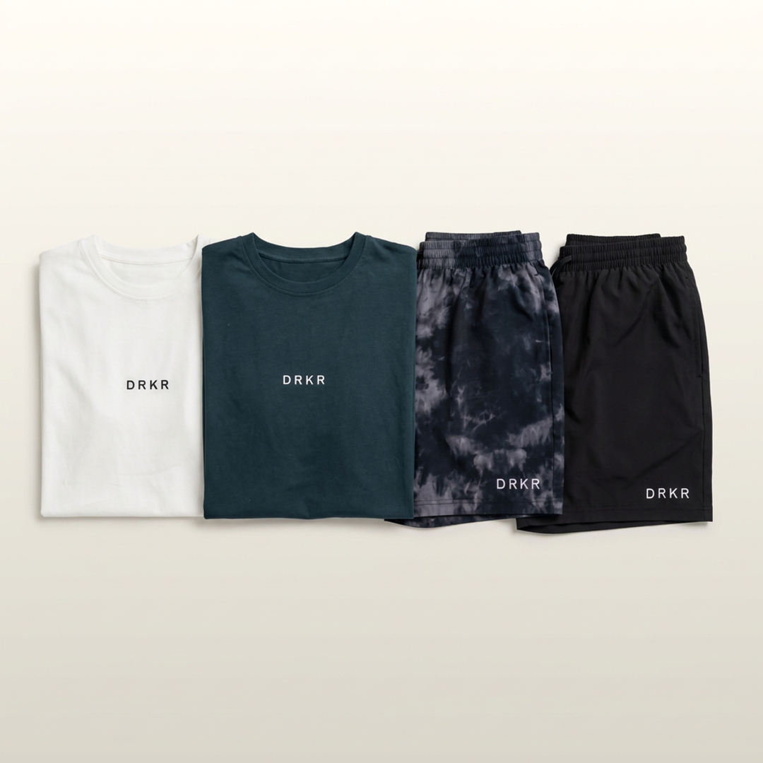 Flat lay of Endure Oversized Tees in white and forest green with Endure 5 inch Shorts in midnight camo and black