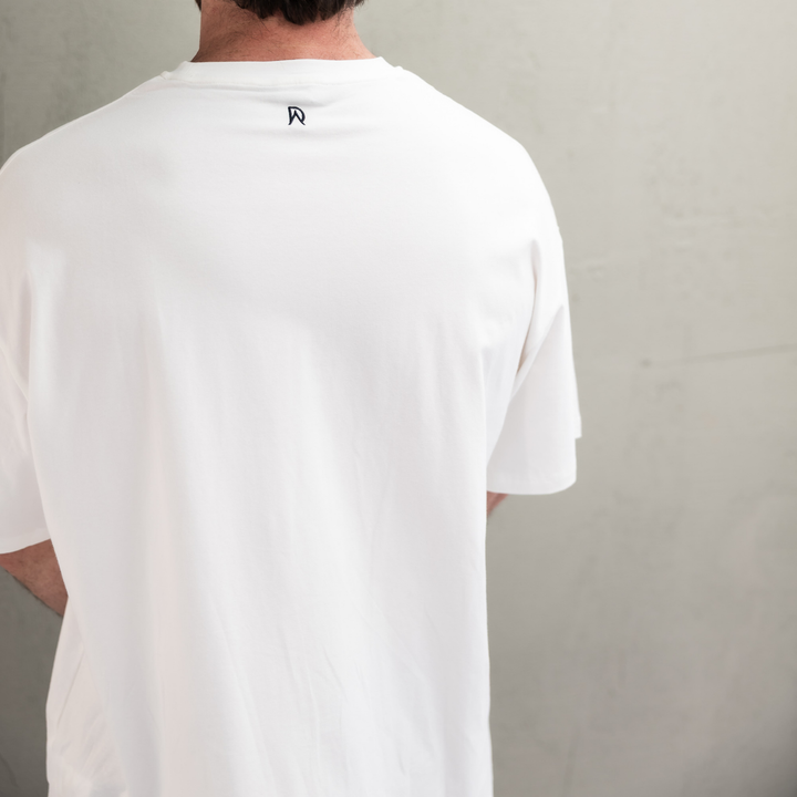Close-up of the DA monogram on the back neck of the white Endure Oversized Tee