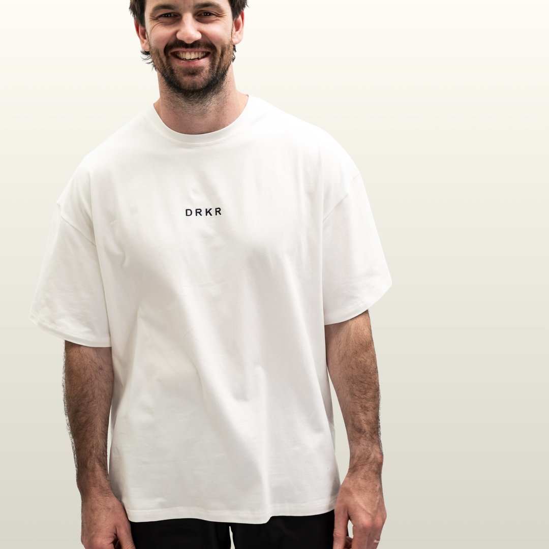 Man wearing the Endure Oversized Tee in white with DRKR chest logo, front view