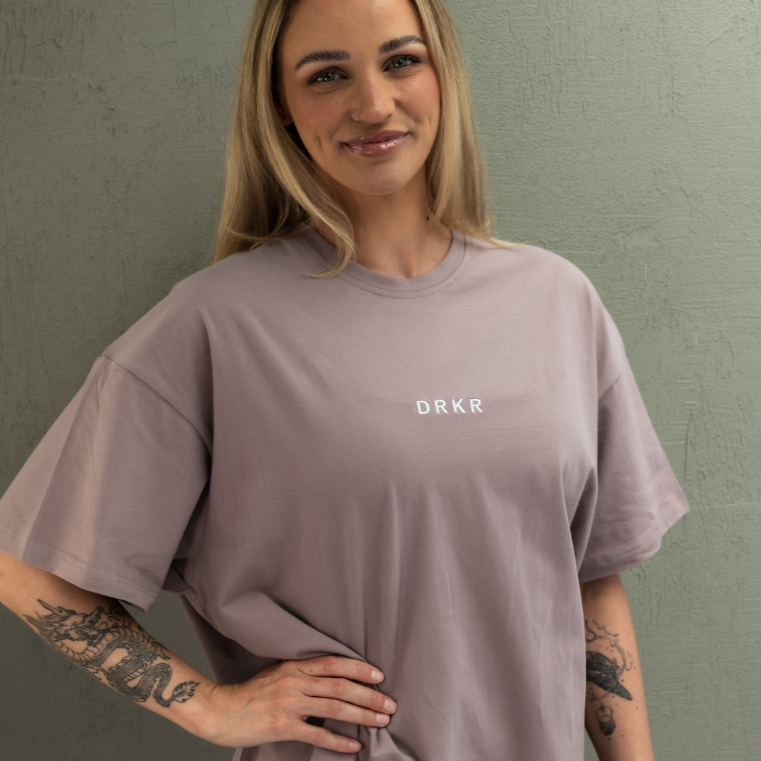 Smiling woman wearing the dusty pink Endure Oversized Tee, close-up front view