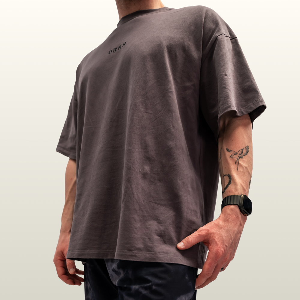 Man wearing the storm grey Endure Oversized Tee, low-angle side view