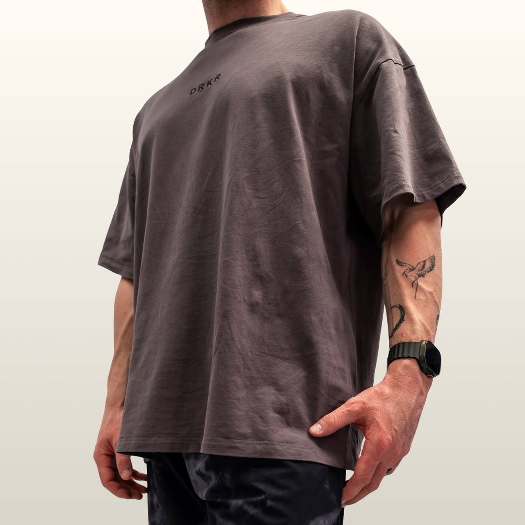 Man wearing the storm grey Endure Oversized Tee, low-angle side view
