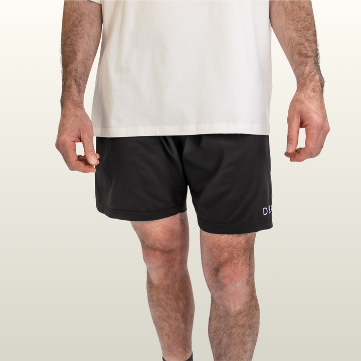 Man wearing the black Endure 7 inch Shorts with a white tee, front view
