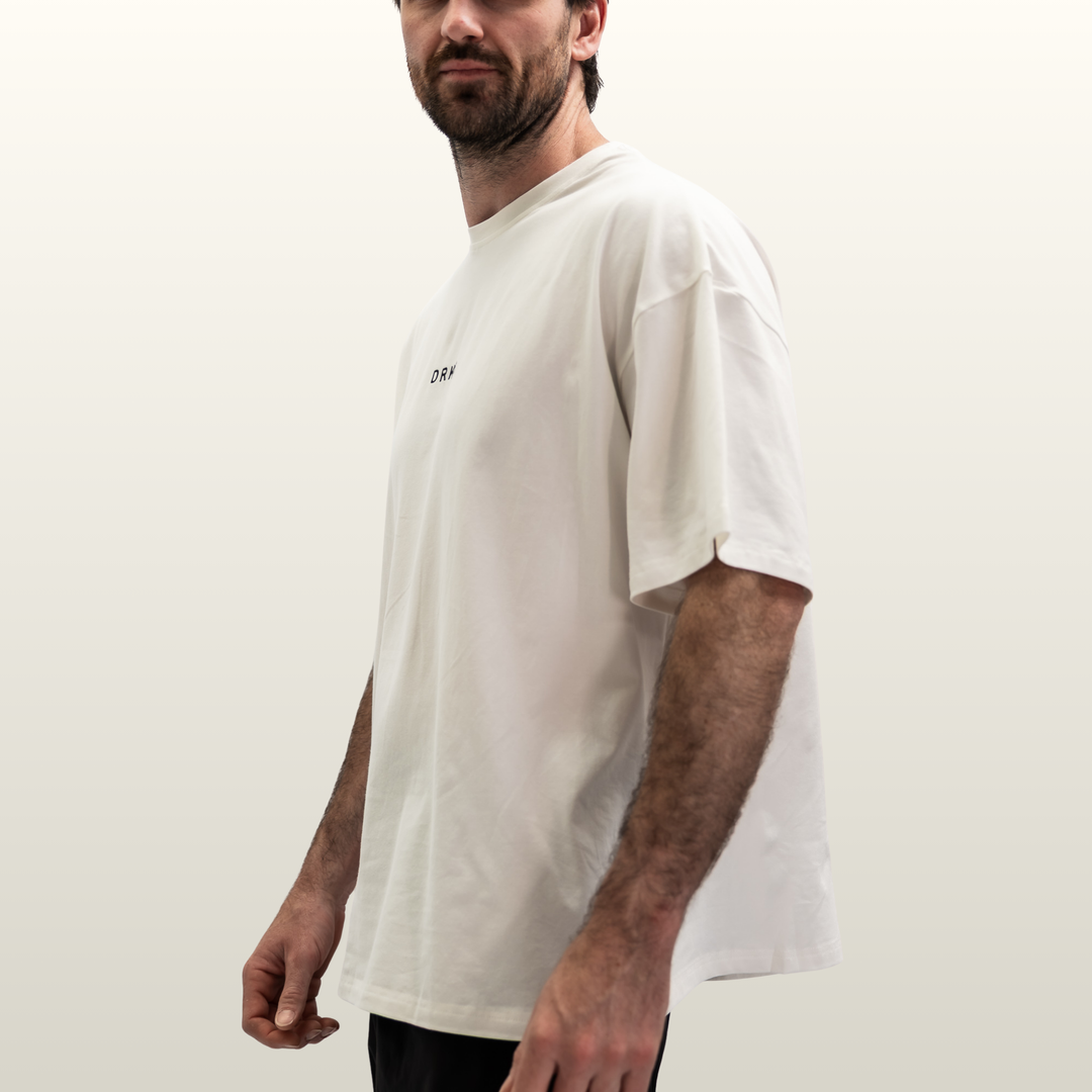 Man wearing the white Endure Oversized Tee, three-quarter side view