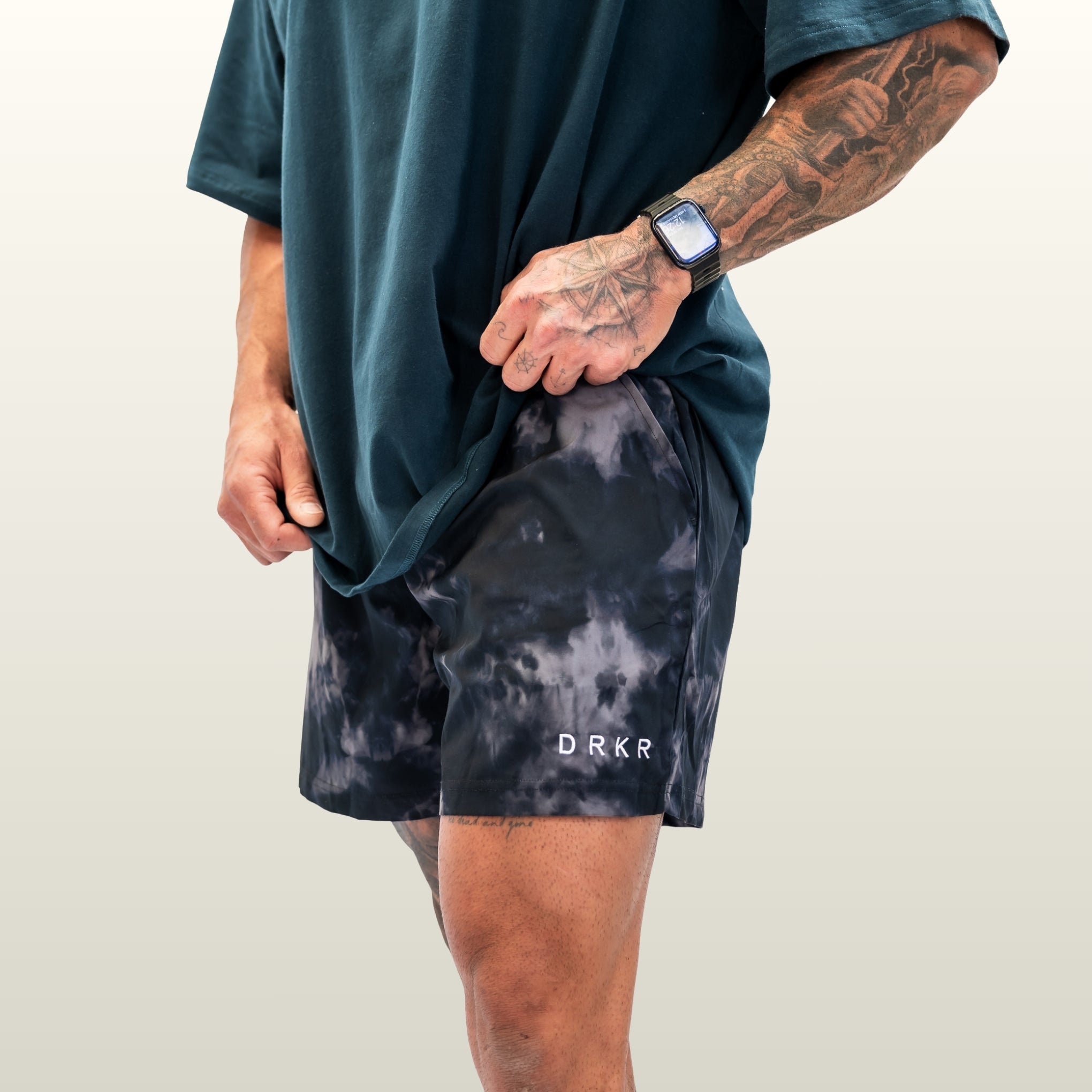 Man wearing the midnight camo Endure 5 inch Shorts, three-quarter view showing the DRKR leg logo
