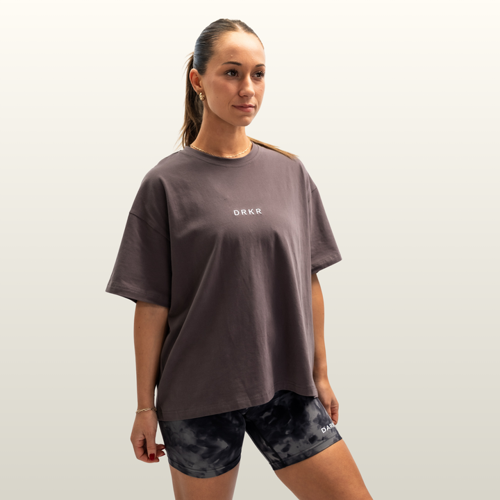 Woman wearing the storm grey Endure Oversized Tee with camo shorts, three-quarter view