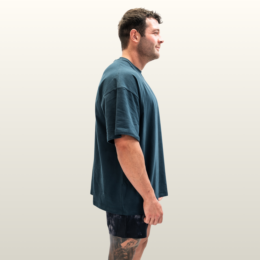 Man wearing the forest green Endure Oversized Tee, side profile view
