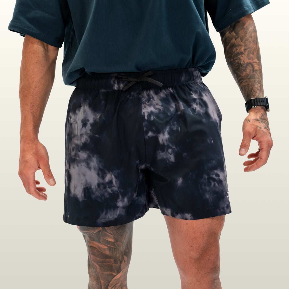 Man wearing the Endure 5 inch Shorts in midnight camo with a forest green tee, front view