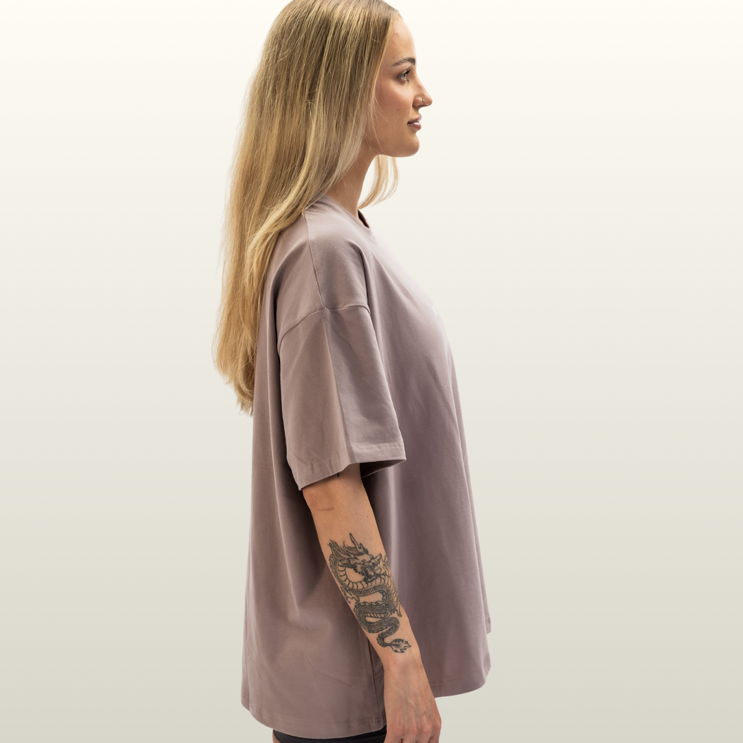 Woman wearing the dusty pink Endure Oversized Tee, side profile view