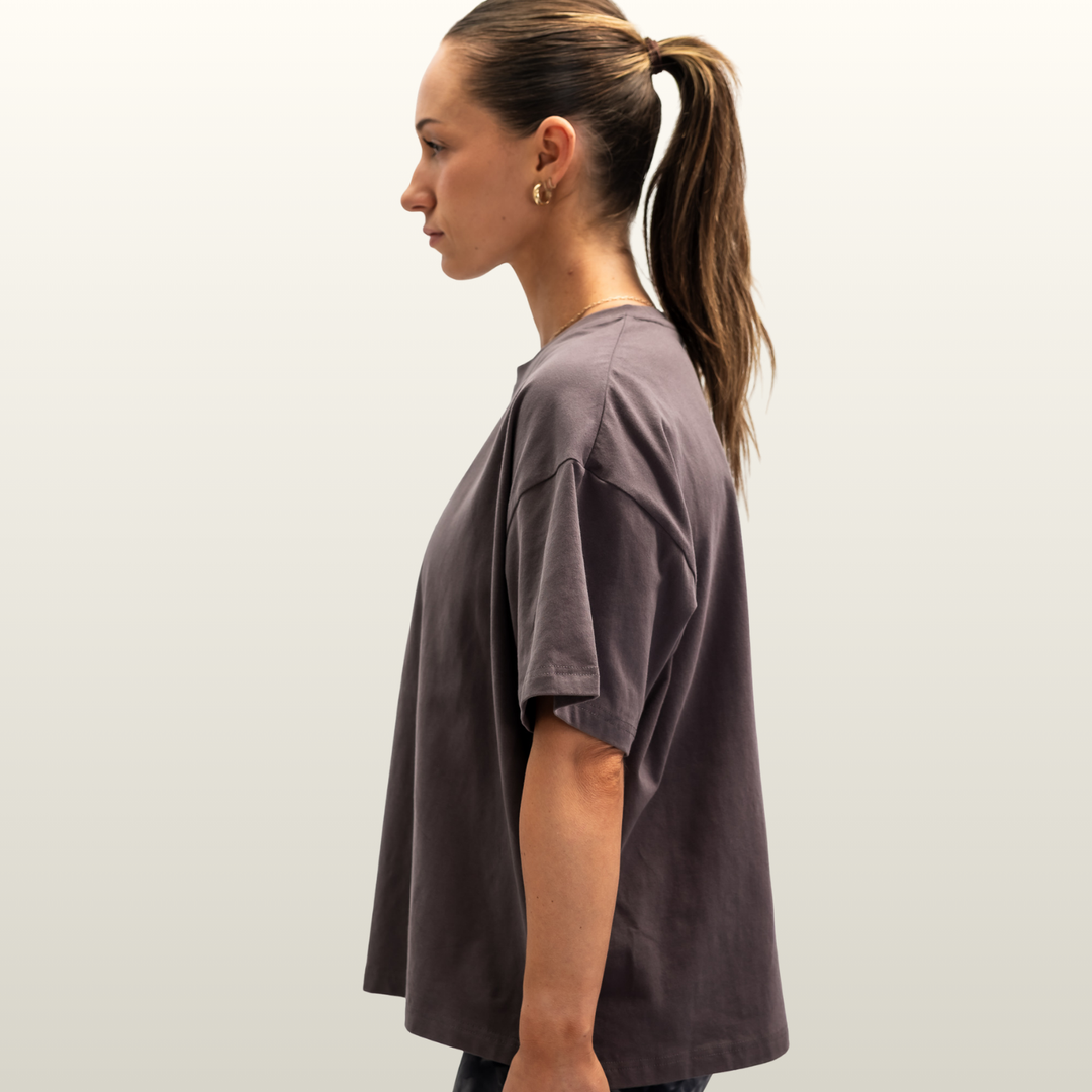Woman wearing the storm grey Endure Oversized Tee, side profile view