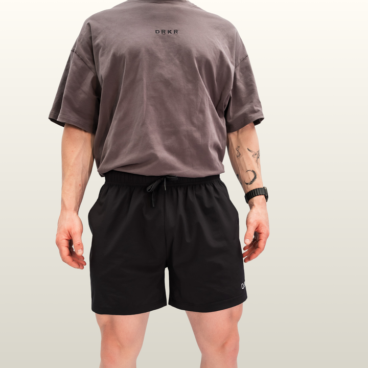 Man wearing the black Endure 5 inch Shorts with a storm grey tee, front view