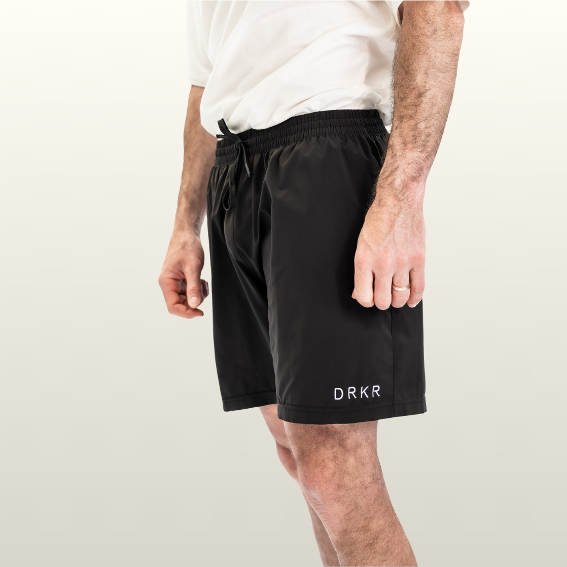 Man wearing the Endure 7 inch Shorts in black with DRKR leg logo, three-quarter view