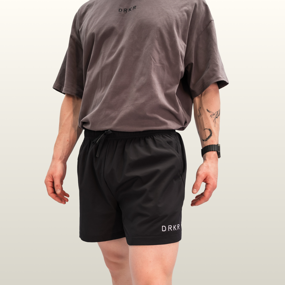 Man wearing the Endure 5 inch Shorts in black with DRKR leg logo, front view