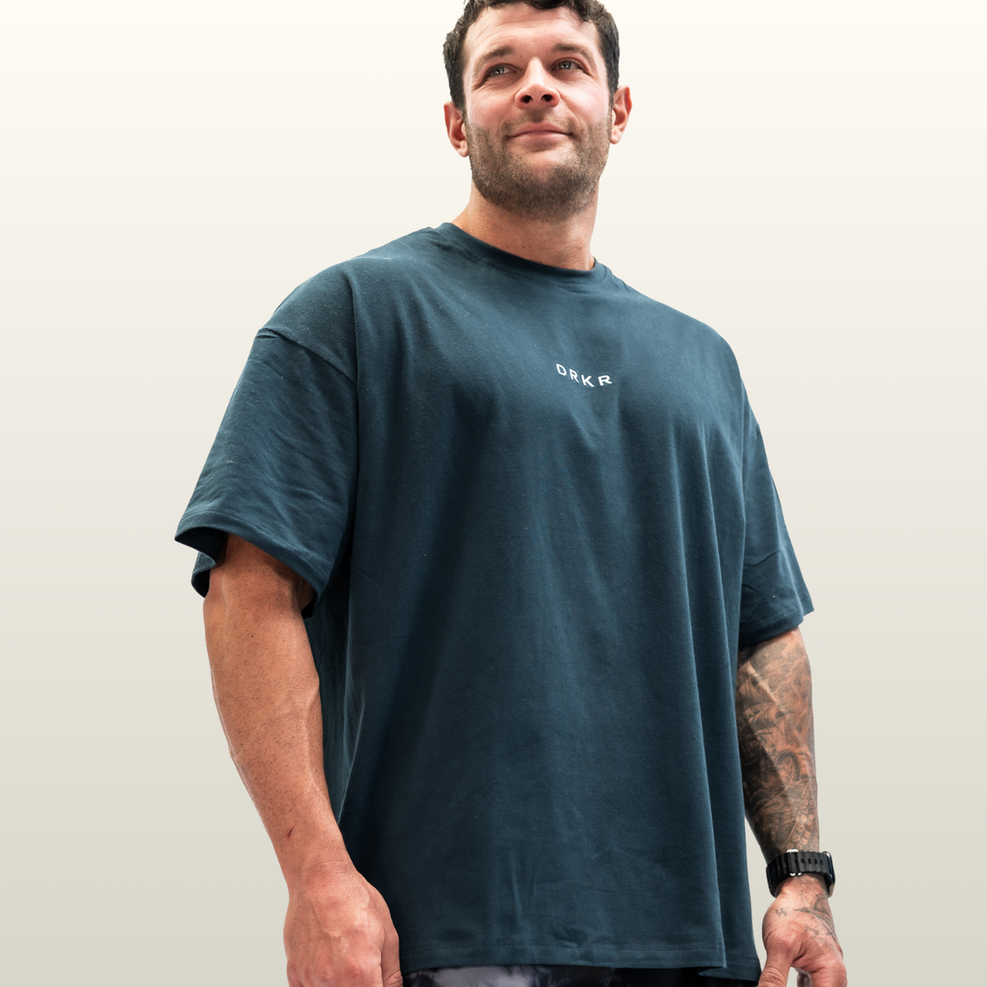 Man wearing the forest green Endure Oversized Tee, low-angle three-quarter view