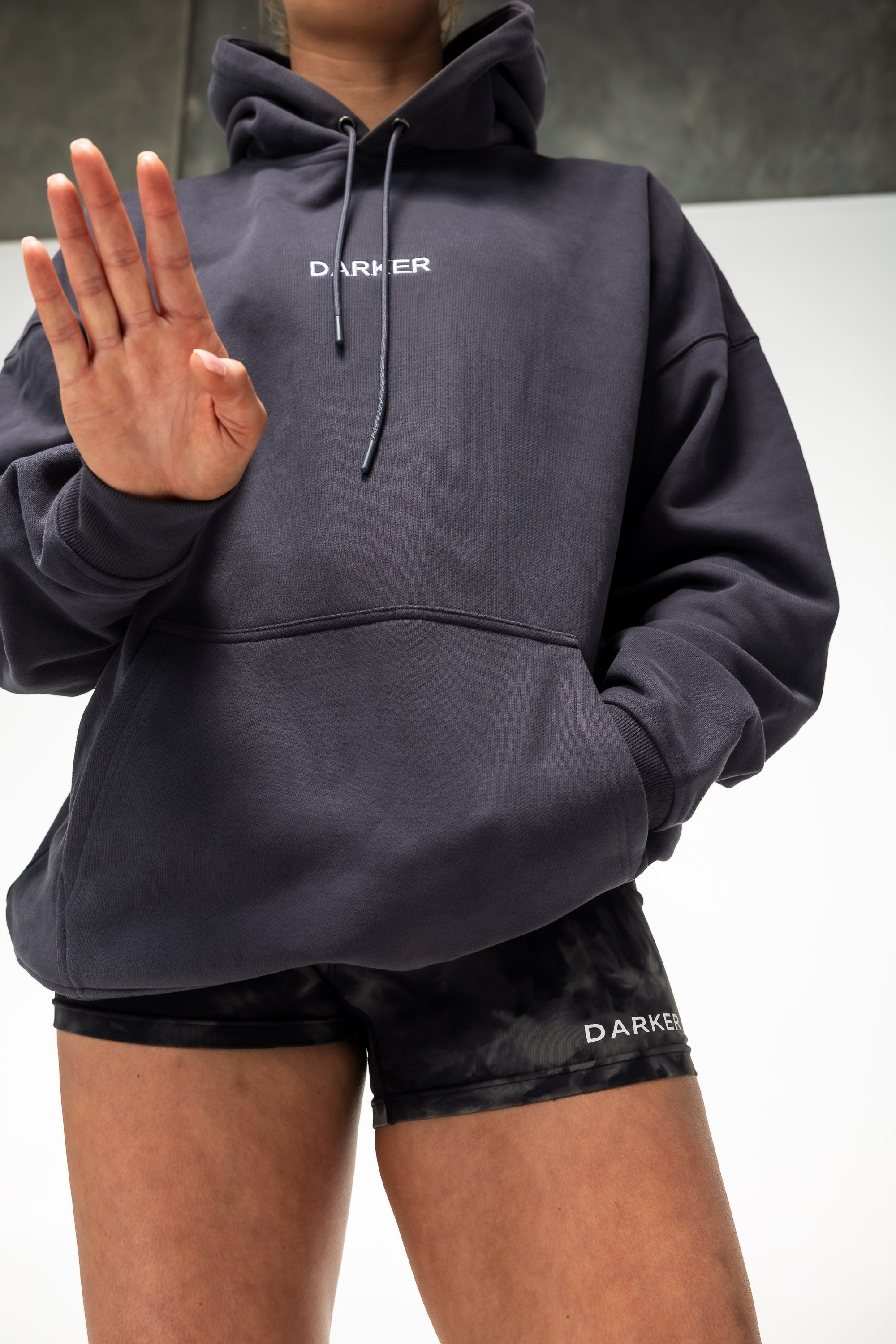 Person wearing a Navy hoodie and black shorts with 'DARKER' branding.