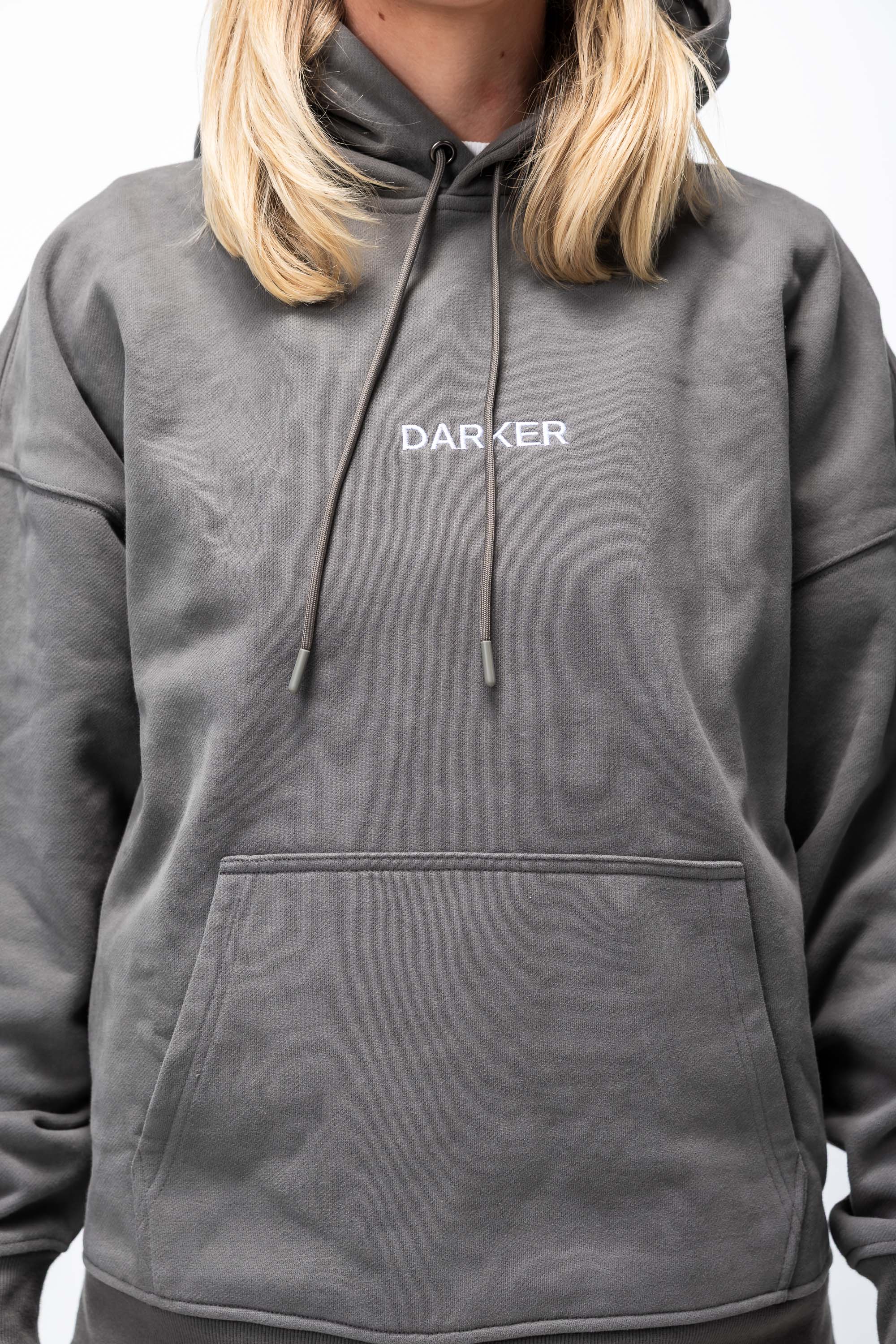 Person wearing a gray hoodie with 'DARKER' logo on a white background