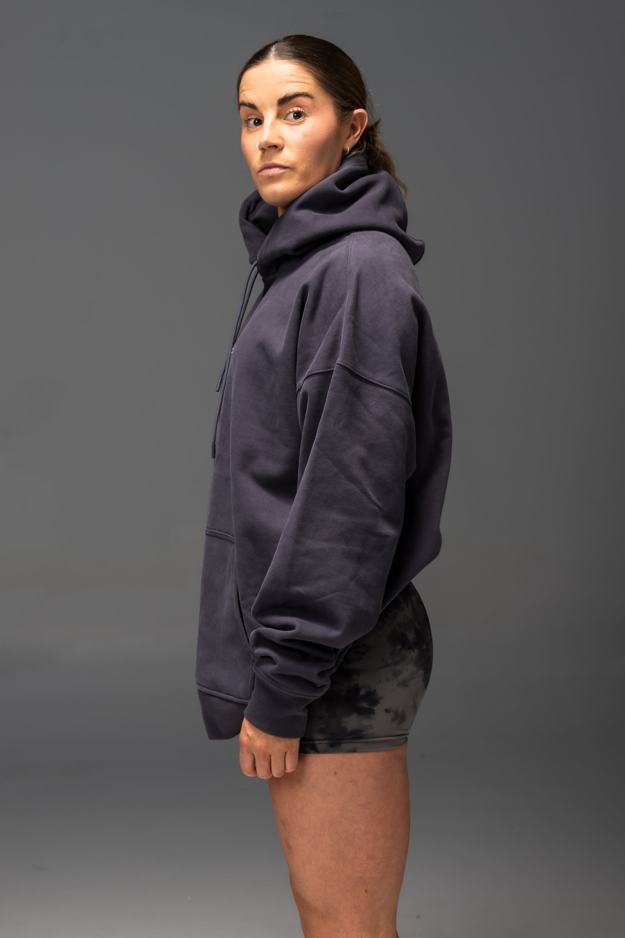 Person wearing a navy hoodie and shorts on a gray background