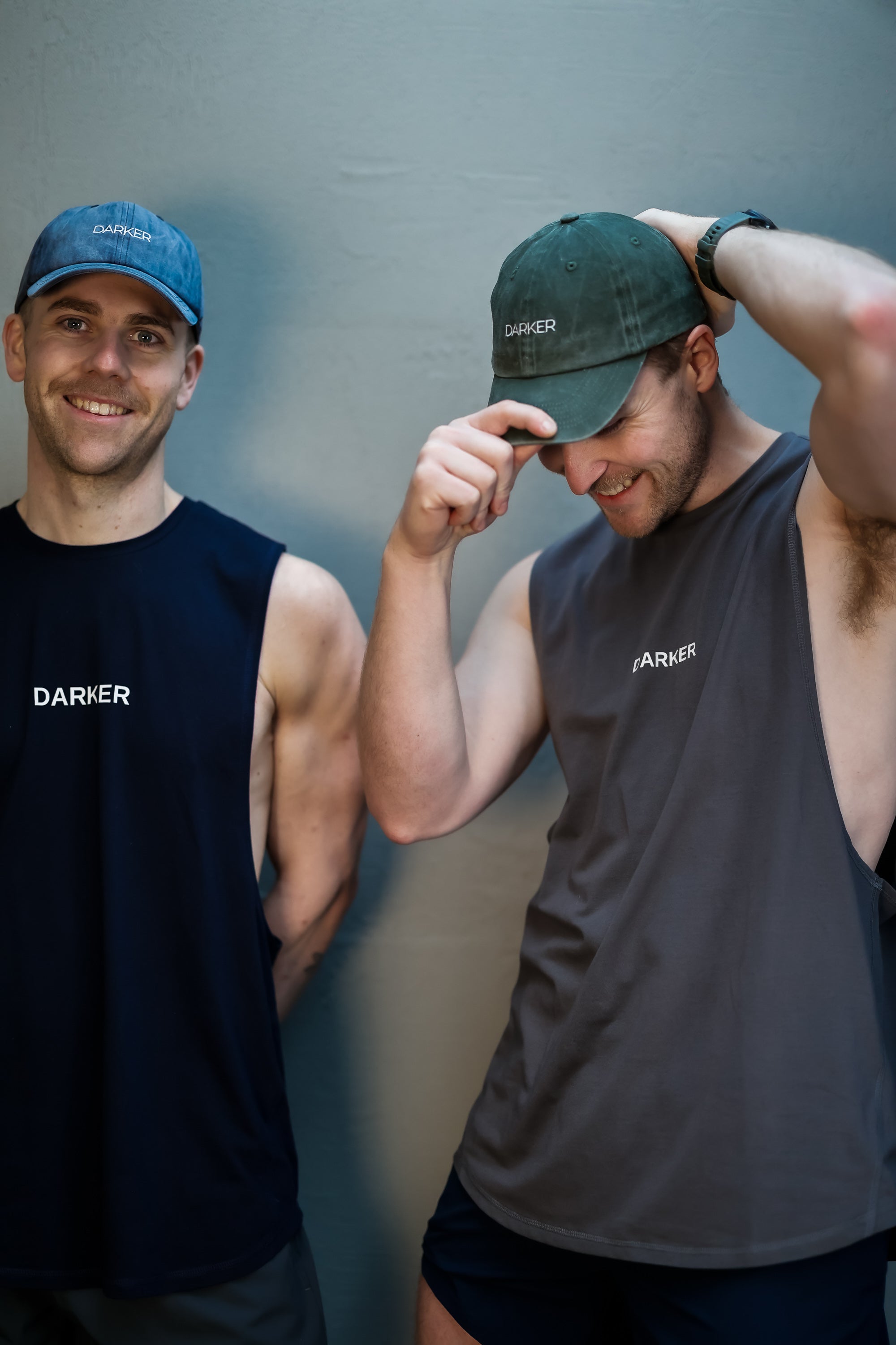 Two men wearing Darker branded clothing and hats against a gray background