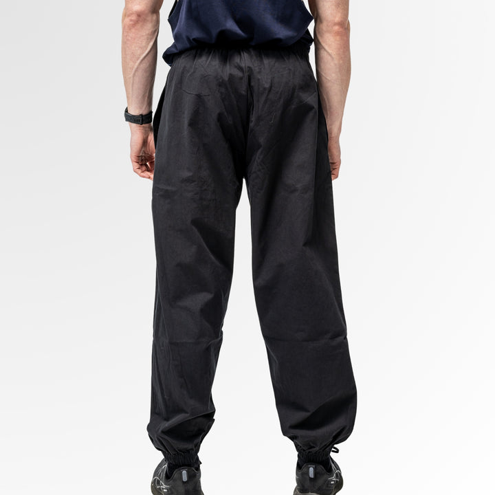 Person wearing black drift pants on a white background, photo taken from the back