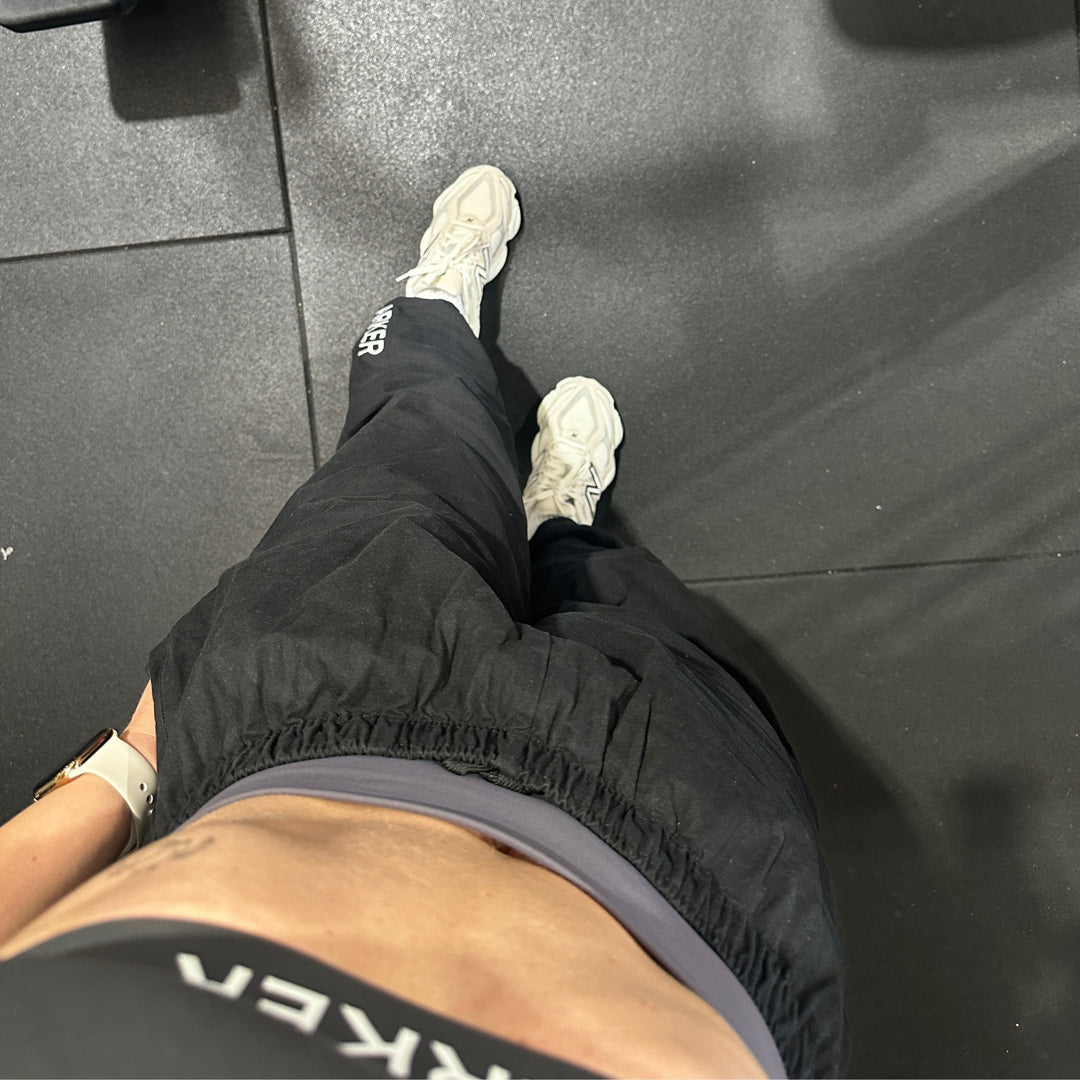 Person wearing black pants and white sneakers on a dark tiled floor