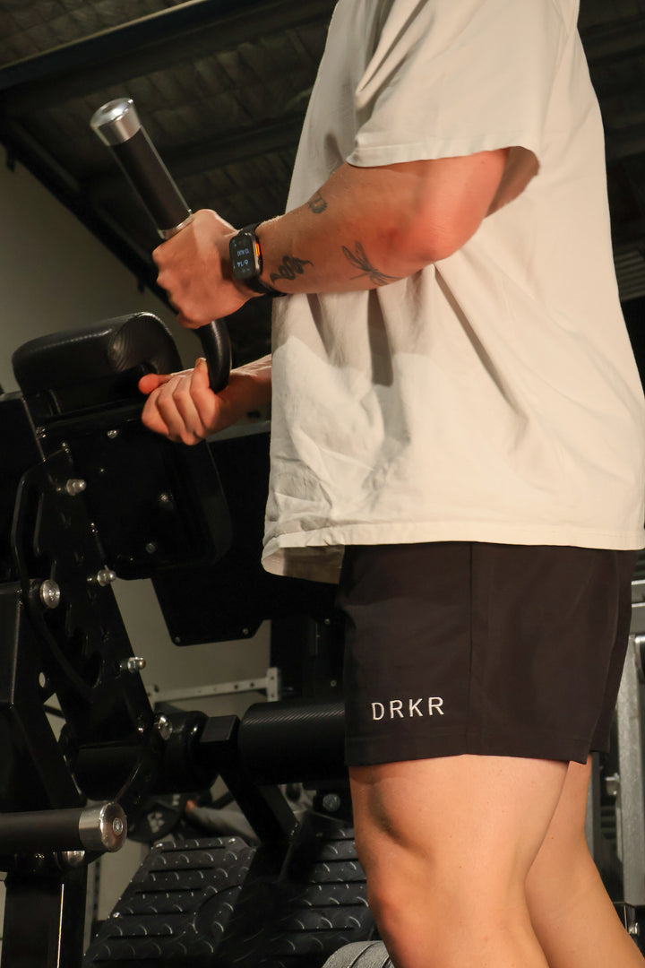 Close-up of the black Endure 5 inch Shorts on a man training on a gym machine