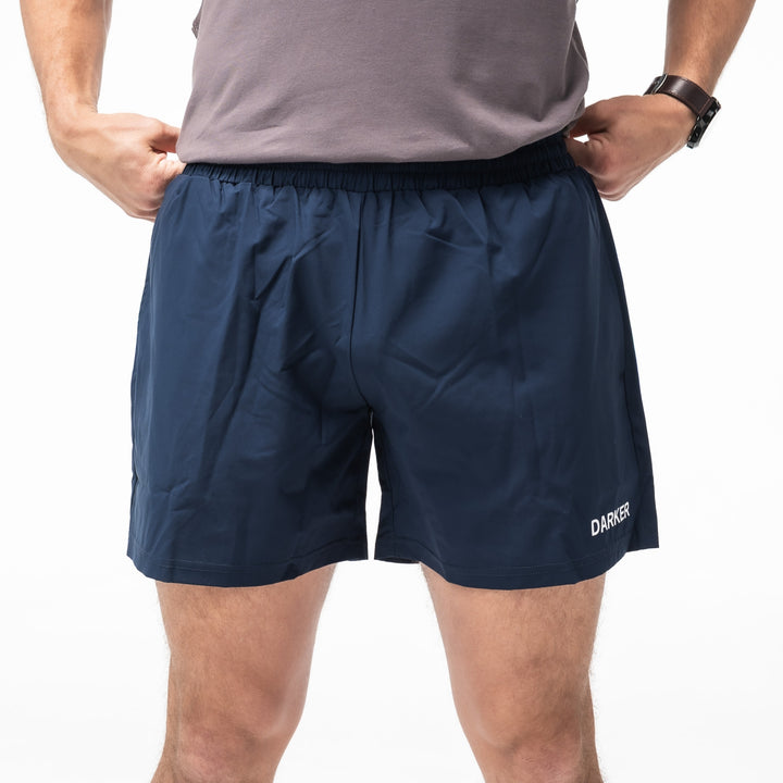 Navy athletic shorts with 'DARKER' branding on a white background