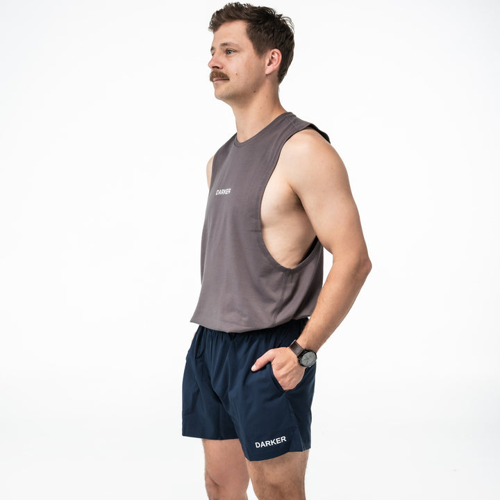 Man wearing a gray sleeveless shirt and navy shorts with 'Darker' branding on a white background