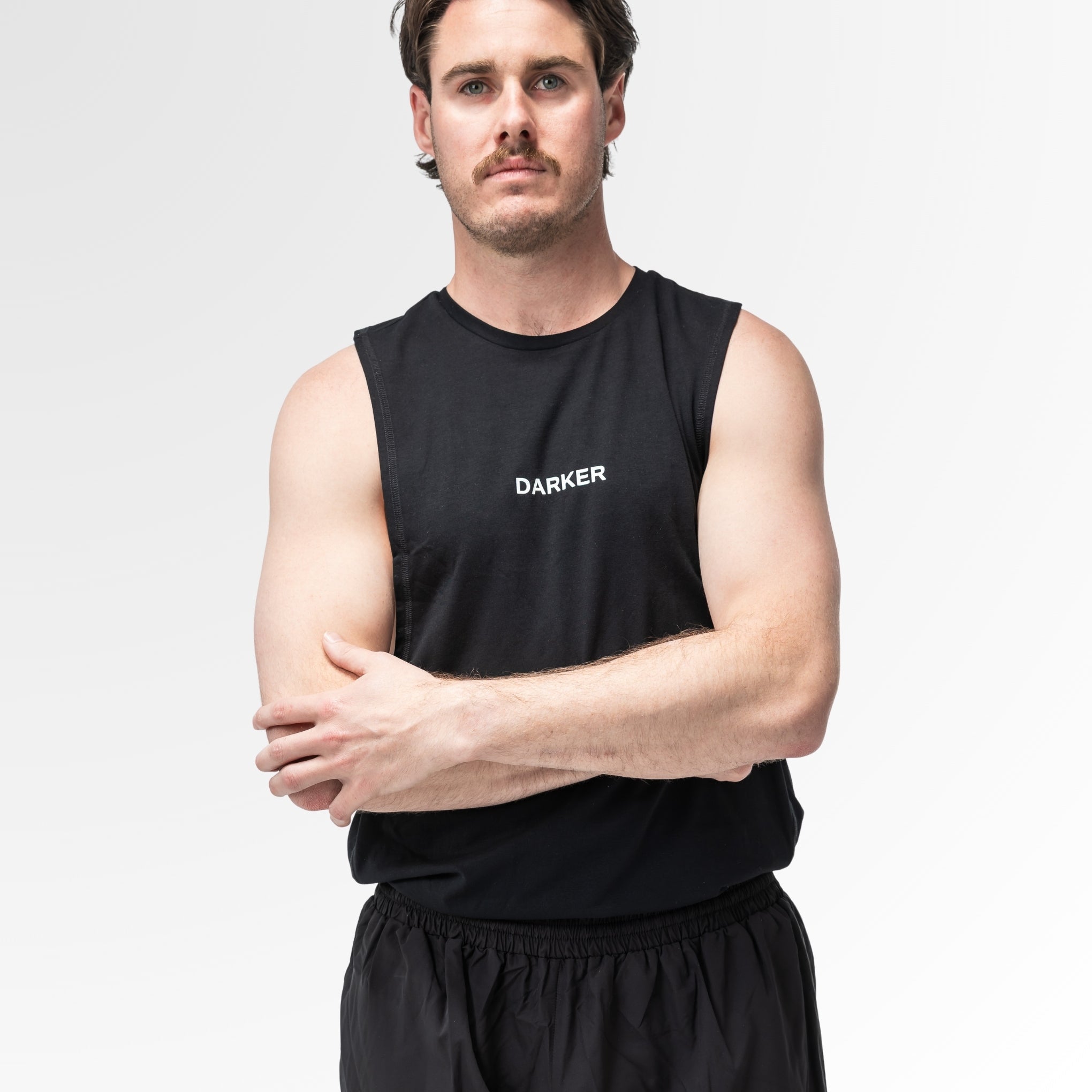 Man wearing a black sleeveless shirt with 'DARKER' logo on a white background