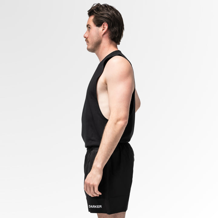Man wearing a black tank top and shorts on a white background