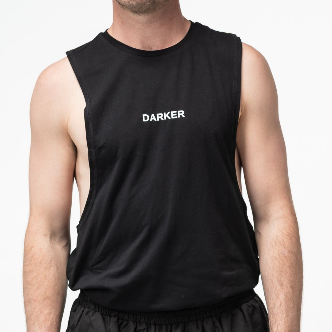 Person wearing a black tank top with 'DARKER' printed on it against a white background