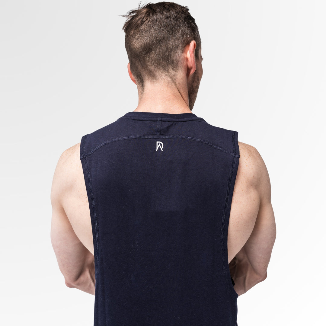 Man wearing a navy sleeveless shirt with a logo on the back against a light gray background