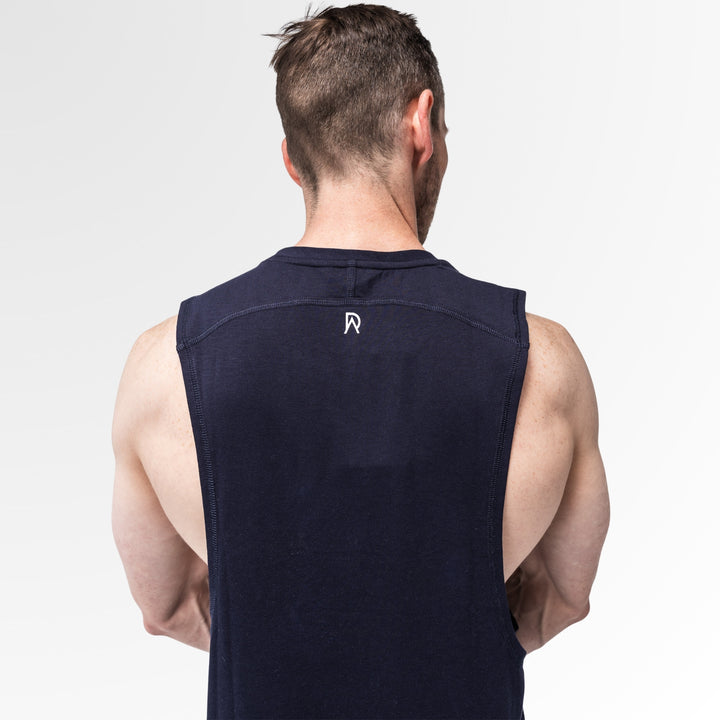 Man wearing a navy sleeveless shirt with a logo on the back against a light gray background